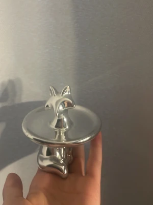 Smyckesfat i form av silverfärgad räv  - Unikt smyckesfat i metall med en söt rävformad figur i mitten. Perfekt för att förvara ringar, örhängen eller andra småsmycken. Fatet har en blank, silverfärgad finish och en rund form som ger en modern och stilren känsla till ditt rum.
