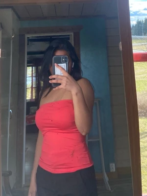 Röd bandeau tubtopp - Säljer en röd bandeau tubtopp som sitter tight och är perfekt för sommaren. Toppen är ärmlös och har en enkel, stilren design utan mönster eller detaljer. Passar dig som vill ha en basic och snygg topp till din garderob.