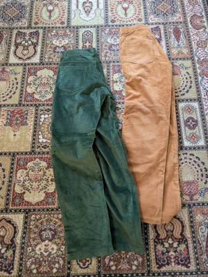 Två par manchesterbyxor gröna & beige/orange - Två par manchesterbyxor i klassisk modell, ett par i mörkgrönt och ett par i ljusbrunt. Båda har raka ben, fickor fram och bak samt dragkedja och knapp i midjan. Perfekta för dig som gillar retrostil och mjuka material. Står ingen storlek men är tighta för mig som har 34/36. Skulle säga att de känns mer som 34. Längden skulle jag säga passar någon från 155-160 cm