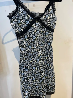 Blå blommig klänning  - En blå blommig klänning med svarta spets detaljer från H&M, storlek XS.
