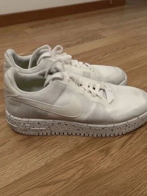 Vita Nike Air Force 1 sneakers i mycket bra skick - Säljer ett par vita Nike Air Force 1 sneakers med ovandel i mesh och textil. Skorna har en vit sula med svarta prickar och klassisk Nike swoosh på sidan. Lågt skaft och snörning framtill. Perfekta för dig som gillar stilrena och sportiga sneakers. I mycket bra skick, helt nytvättade.