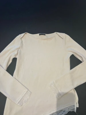 Beige långärmad topp med spetsdetaljer - Säljer en beige långärmad topp med fina spetsdetaljer vid ärmslut och nederkant. Toppen har en enkel och stilren design med rund halsringning och mjukt material som känns skönt mot huden.