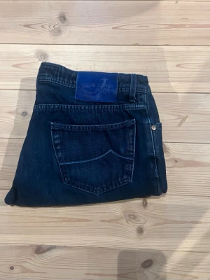 Mörkblå jeans från Jacob Cohen - Snygga mörkblå jeans från Jacob Cohen med klassisk femficksmodell och kontrastsömmar. Jeansen har en blå patch med logga bak i midjan och är tillverkade i ett mjukt denimtyg som ger en skön passform. Priset är inte hugget i sten👏
