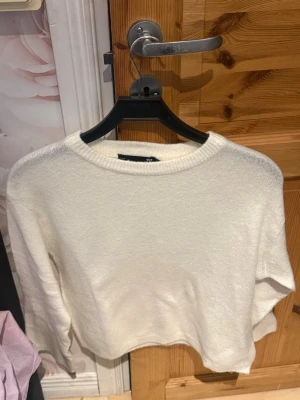 Vit stickad tröja med rund hals - En enkel och stilren vit stickad tröja med rund hals och långa ärmar. Tröjan har en rak passform och är gjord i ett mjukt material som känns skönt mot huden. Perfekt att matcha med jeans eller kjol för en clean look.