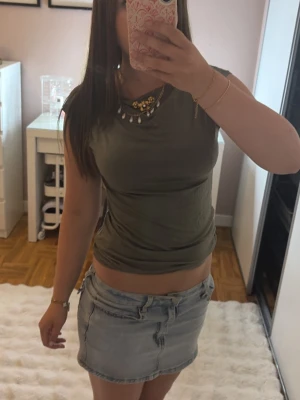 Olivgrön ärmlös topp - En enkel och stilren olivgrön topp i mjukt material. Modellen är ärmlös med rak passform och rund halsringning. Perfekt att matcha med jeans eller kjol för en clean look💋