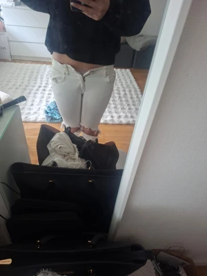 Vita slitna jeans med hål vid knäna - Säljer ett par vita jeans med låg midja och hål vid knäna. Jeansen har fem fickor och råa benslut för en trendig look. Dem e bowt cup och dem når ner till marken för mig å ja e 165💕