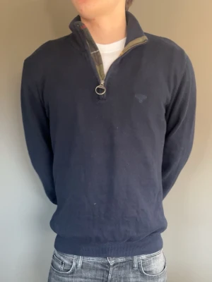 Mörkblå half-zip tröja Barbour - Mörkblå tröja från Gant med halv dragkedja och ståkrage. Tröjan har ribbade muddar vid ärmslut och nederkant samt diskret Gant-logga på bröstet. Perfekt till jeans och funkar året runt. Materialet känns mjukt och bekvämt.