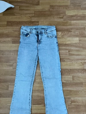 Ljusblå flare jeans low waist - Säljer ett par ljusblå jeans med låg midja och flare-ben. Klassisk femficksmodell med snygga kontrastsömmar och bälteshällor. Jeansen har en avslappnad vibe och är perfekta för dig som gillar retrostil. Materialet är denim i bomull. Storlek S
