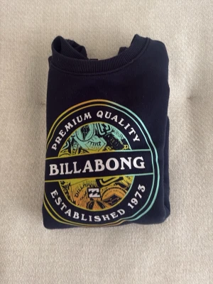 Mörkblå Billabong crewnrck med tryck - Cool mörkblå hoodie från Billabong med färgglatt tryck på bröstet. Gjord i mjukt material och har klassisk passform. Perfekt för dig som gillar grisch och surfstil. Skick: 9/10😮‍💨🔥🍾. Storlek: 13-14 år. Köpt i Frankrike 🇫🇷. Säljer för att den inte passar.