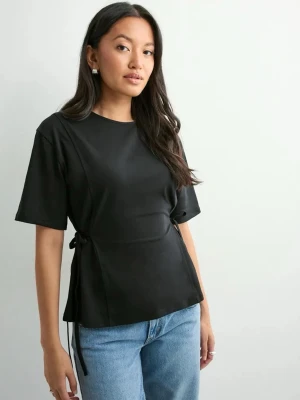 Svart topp med knyt i sidan - En extremt snygg topp som passar till allt! Toppen har en snygg knytning i sidan som ger en cool detalj och lite form. Säljer då den inte riktigt är min stil längre och den har bara legat den jag fick den för ca 4 mån sen.