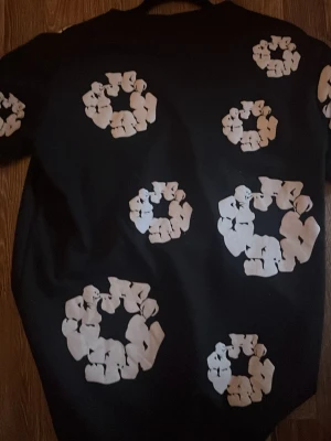 Svart t-shirt med vita cirkelmönster - Cool svart t-shirt med unika vita cirkelmönster över hela plagget. T-shirten har klassisk passform och korta ärmar, perfekt för dig som vill sticka ut med en grafisk look. Materialet känns mjukt och bekvämt mot huden.