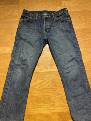 Mörkblå raka jeans - Säljer ett par klassiska mörkblå jeans med rak passform och fem fickor. Jeansen har kontrastsömmar och knappgylf. Perfekta till en avslappnad stil och tillverkade i slitstark denim. Inget synligt märke. Storleken är w31 l32. Pruta gärna