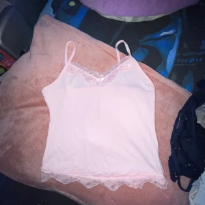 Ljusrosa linne med spets och rosett - NI KAN FÅ DENNA (eller någon annan) MED ETT ANNAT KÖP Supersött ljusrosa linne med tunna axelband, spetskant upptill och nedtill samt en liten rosett framtill. Mjuk och skön bomullskänsla, perfekt för en söt och fenemin look. Passar lika bra till jeans som till kjol.❤️ storleken funkar även för M💕