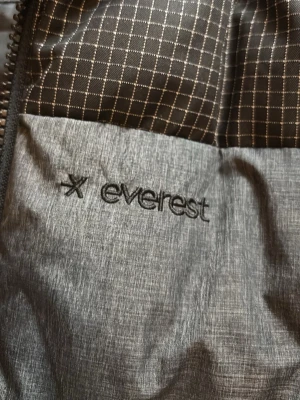 Grå jacka från Everest - Snygg grå jacka från Everest med diskret mönstrad insida och dragkedja. Jackan har en stilren look och är perfekt för dig som gillar funktionella och moderna ytterplagg.