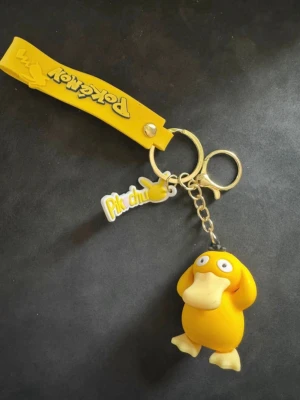 Pokémon nyckelring med Psyduck - Säljer en gul nyckelring med Psyduck-figur från Pokémon. Nyckelringen har även en gul Pikachu-tag och en rem med Pokémon-logga. Perfekt för dig som gillar anime och vill ha något unikt till dina nycklar eller väska.