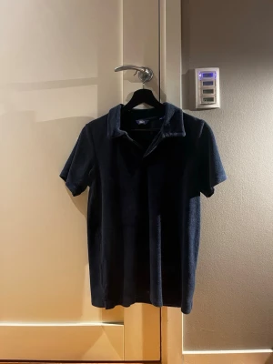 Mörkblå piké t-shirt i bomull - Säljer en mörkblå piké t-shirt i frotté eftersom den aldrig kommer till användning . Perfekt för dig som gillar en avslappnad men ändå stilren look. Passar till jeans eller shorts för en enkel outfit. Passar storlek S