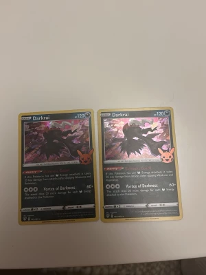 Pokémonkort Darkrai Pikachu-stämpel - Två samlarkort med Darkrai från Pokémon, båda med Pikachu-stämpel i hörnet. Kortens design är mörk med holografisk effekt och guldkant. Text och illustrationer är på engelska. Perfekt för Pokémon-samlare eller som cool dekoration.