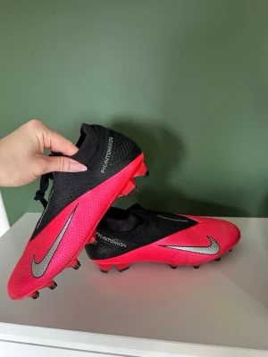 Nike Phantom Vision röd/svart fotbollssko - Snygga Nike Phantom Vision fotbollsskor. Använda få gånger så dem är i fint skick. Kommer inte till användning då jag köpte andra i samband. Köptes för 3000kr