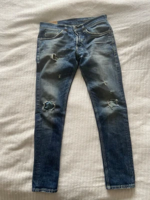 Dondups med slitningar - Säljer ett par Dondups jeans med slitningar och hål på både fram och baksida. Skulle säga att jeansen är slim fit. Kom gärna med ett prisförslag!