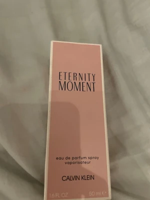 Calvin Klein Eternity Moment parfym - Eternity Moment från Calvin Klein är en elegant parfym i en rektangulär glasflaska med transparent lock. Doften kommer i en rosa kartong och flaskan rymmer 50 ml eau de parfum spray. Perfekt för dig som gillar fräscha och feminina dofter.