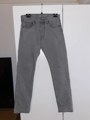 Gråa 501 jeans från Levi’s - Säljer ett par grå 501 jeans från Levi’s. Perfekta för en clean och avslappnad look. Klassiska och stilrena! Tidlösa och fungerar i alla tillfällen! Inga defekter! Hör av dig för fler bilder!