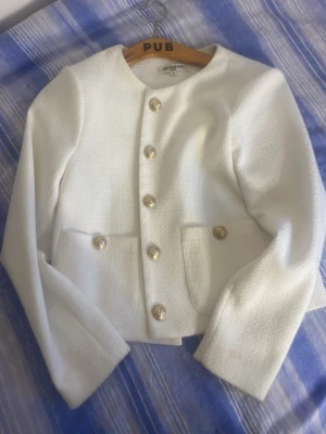 Vit kavaj med guldfärgade knappar - Stilren vit kavaj köpt på Sturegallerian. Köpt för 3000 kronor 