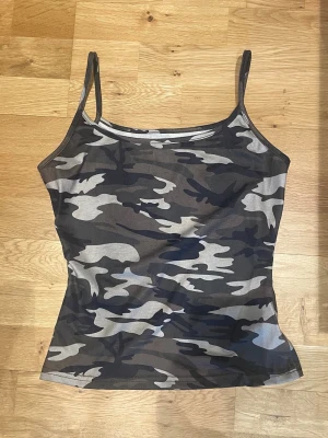 Camo mönstrad linnetopp💕 - Snygg camouflagemönstrad linnetopp med smala axelband. Toppen har en tight passform och är perfekt för dig som vill sticka ut med en edgy stil. Materialet känns mjukt och stretchigt, vilket gör den bekväm att bära hela dagen.💕