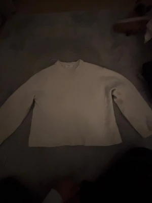 Beige stickad tröja med rund hals - En enkel och stilren beige stickad tröja med rund hals och långa ärmar. Tröjan har ribbstickade muddar och är gjord i ett mjukt material som passar perfekt för lager-på-lager. Perfekt för dig som gillar minimalistisk stil.