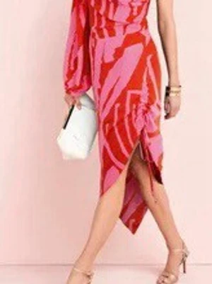 Rosa och röd asymmetrisk klänning size 38/40 - Säljer en färgstark klänning med rosa och röda mönster, asymmetrisk fåll och en ärm. Klänningen har dragsko i sidan och en axelbandsdetalj. Perfekt för dig som vill sticka ut med en unik och trendig look. Size : 38/40