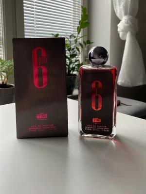 6pm Eau de Parfum från TRI - Säljer en 6pm Eau de Parfum från TRI. Flaskan är genomskinlig med röd text och har en rund, silverfärgad kork. Doften kommer i en stilren rektangulär glasflaska och med tillhörande svart och röd kartong. Volymen är 100 ml.