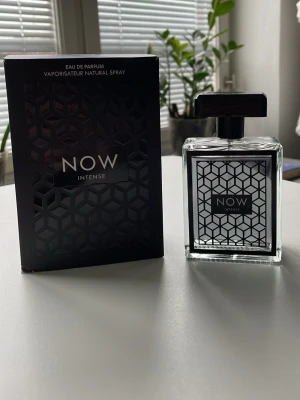 NOW Intense Eau de Parfum - Snygg parfymflaska från NOW med doften Intense. Flaskan är fyrkantig i genomskinligt glas med svart geometriskt mönster och svart etikett. Kommer med matchande svart förpackning med samma mönster. Perfekt för dig som gillar stilrena och moderna designer.