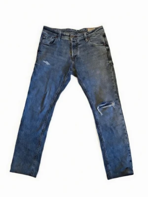 Blå Jack&Jones jeans med slitningar  - Ett par schyssta urtvättade blåa jean från Jack&Jones med slitningar. Passfrom Regular/Slim. Storlek 29W/30L