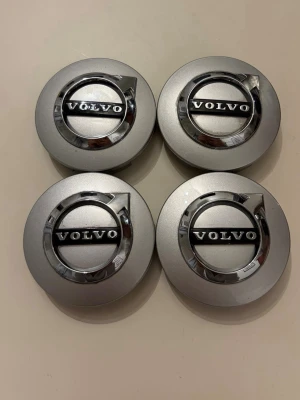 Volvo centrumkåpor i silver - Fyra stycken runda centrumkåpor i silverfärg med Volvo-logga i svart och krom. Tillverkade i plast och metall, passar till Volvobilars fälgar. Snygg detalj för att ge bilen ett fräscht utseende.