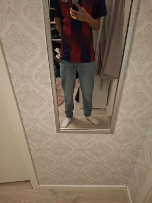 Ljusblå raka jeans i denim - Säljer ett par ljusblå jeans med rak passform och klassisk femficksdesign. Jeansen har normal midja och är tillverkade i mjukt denimtyg som ger en avslappnad och stilren look. Perfekta för dig som gillar enkel och tidlös stil. L32