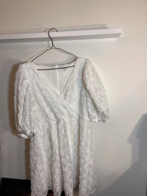 Vit klänning M - Supersöt vit kortklänning från Bubbleroom med v-ringad omlottfront och puffiga kortärmar. Passar till student och avslutningar