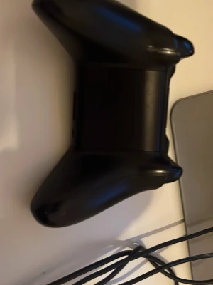 Svart Xbox One handkontroll - Säljer en svart Xbox One handkontroll med klassisk design. Kontrollern har två analoga spakar, styrkors, samt A, B, X och Y-knappar i färg. Tillverkad i matt plast med ergonomiskt grepp, perfekt för gaming på konsol eller PC.