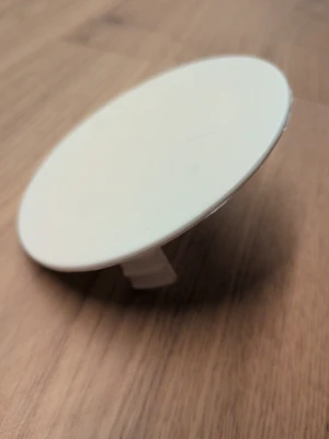 Vit rund mobilhållare till skal - Säljer en vit, rund mobilhållare som fästs på baksidan av mobilskalet. Perfekt för bättre grepp eller som stativ när du kollar på videos. Tillverkad i plast och har en enkel, stilren design utan mönster eller logga.