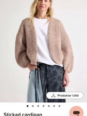 Beige stickad cardigan från Lindex  - Mysig beige stickad cardigan med ballongärmar från Lindex. Cardiganen är öppen framtill och har en avslappnad passform. Perfekt att slänga över en t-shirt för en cool och enkel look. Skriv till mig för bilder