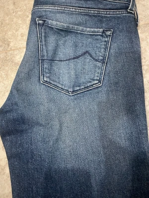 Blå jeans från Jacob Cohen - Snygga blå jeans från Jacob Cohen med klassisk femficksdesign och diskreta slitningar. Jeansen har raka ben och är tillverkade i mjukt denim-material med tydliga sömmar. Perfekta för dig som gillar stilrena och exklusiva jeans.