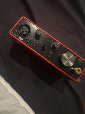 Focusrite Scarlett Solo ljudkort - Säljer ett rött Focusrite Scarlett Solo ljudkort med metallchassi. Perfekt för dig som vill spela in musik eller podd, med XLR-ingång, gain-reglage och stor volymratt. Kompakt och stilren design med tydliga kontroller på framsidan.