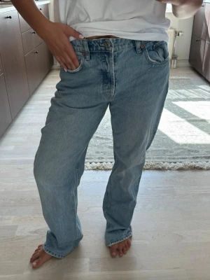 Ljusblå raka jeans - Säljer ett par ljusblå jeans med rak passform och klassisk femficksdesign. Jeansen har hög midja och stängs med knapp och dragkedja. Perfekta för en avslappnad och trendig look.