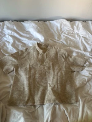 Beige stickad trekvarts Gina Tricot - Kortärmad stickad t-shirt i beige från Gina Tricot. Tröjan har rund halsringning och ribbade kanter vid ärmslut och nederkant. Tillverkad i en mjuk ullblandning som känns både trendig och bekväm. Strl S men skulle säga att den är stor i storleken. Nyskick. 