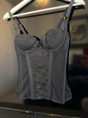 vintage spetskorsett - Snygg svart korsett från Love Lingerie i storlek . Modellen har vadderade kupor, justerbara axelband och dekorativ rosett framtill. Tillverkad i genomskinlig mesh och spets med fina detaljer. Perfekt för dig som vill ha en feminin och stilren look.