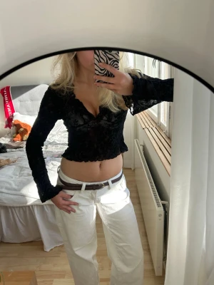 Svart croppad blus med spetsdetaljer - Snygg svart croppad blus med v-ringning och långa ärmar. Endast använd fåtal gånger