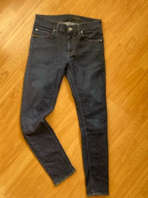 Mörkblå tiger of sweden jeans - Säljer ett par mörkblå slim jeans med klassiska fem fickor. Jeansen har smal passform och är gjorda i stretchigt denimtyg för extra komfort. Snygga kontrastsömmar och knappgylf framtill.