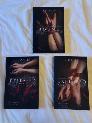Highgate Preparatory Academy trilogi - Säljer tre böcker av Rosa Lee: Bound, Released och Captured. Böckerna har mörka omslag med motiv av händer och röda band, vilket ger en mystisk och romantisk känsla. Perfekt för dig som gillar spännande och känslosam skönlitteratur.
