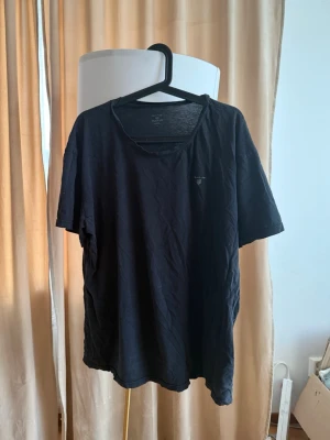 Svart t-shirt från GANT - Klassisk svart t-shirt från GANT med rund halsringning och diskret logga på bröstet. Tillverkad i mjuk bomull och har en avslappnad passform som passar perfekt till jeans eller shorts.