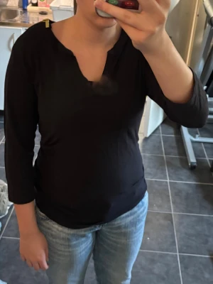 Svart blus med dragkedjedetaljer Micheal Kors - Stilren svart blus från Michael Kors med långa ärmar och snygga guldfärgade dragkedjor på axlarna. Blusen har en djup V-ringning och är tillverkad i ett mjukt tyg som ger en avslappnad look. Perfekt att matcha med jeans eller kjol. storlek M.