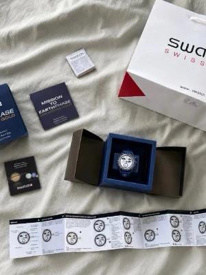 Blå Omega x Swatch MoonSwatch - Säljer en ny/oanvänd klocka i riktigt fint skick. Blå modell från Bioceramic MoonSwatch Collection. Full set med box, påse, papper, manual och allt som syns på bilden. Perfekt för samlare eller vardagsbruk.  Skickas snabbt och säkert. DM:a vid frågor eller för fler bilder.
