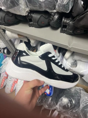Svarta och vita sneakers - Snygga chunky sneakers i svart och vitt med glansiga svarta detaljer och vit mesh. Skorna har en tjock vit sula och vita skosnören. Perfekt för dig som vill sticka ut med en modern och sportig look.